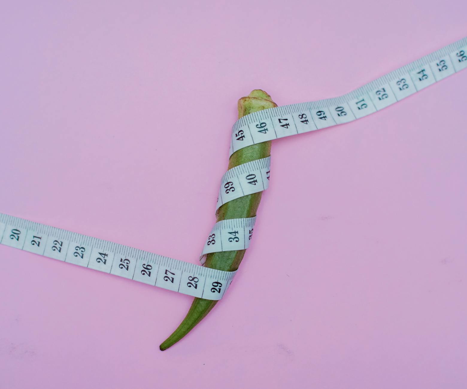 Zielona papryczka chili owinięta miarą na liliowym tle