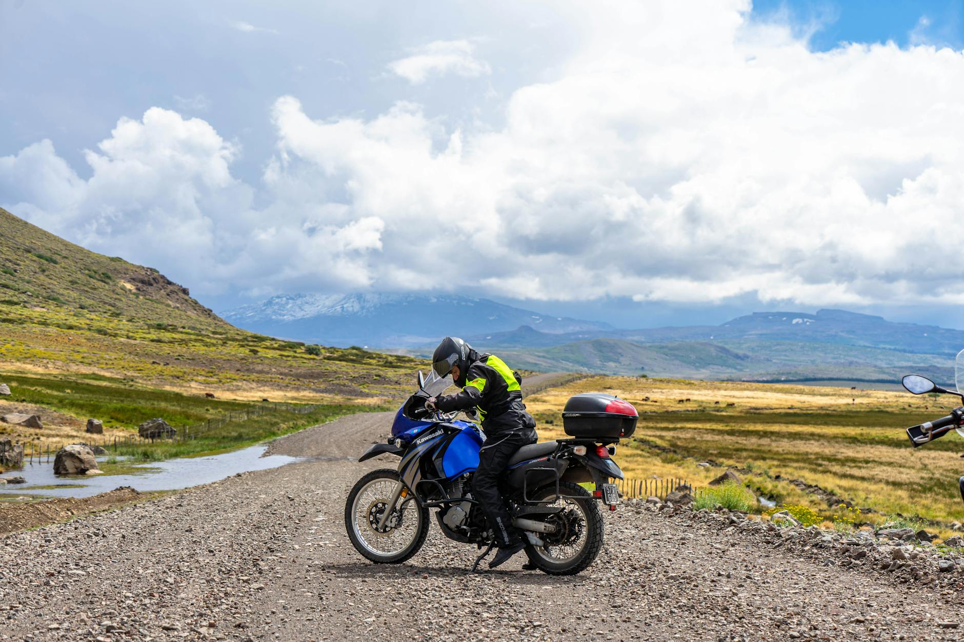 Motocyklista jedzie przez górzysty krajobraz pod zachmurzonym niebem