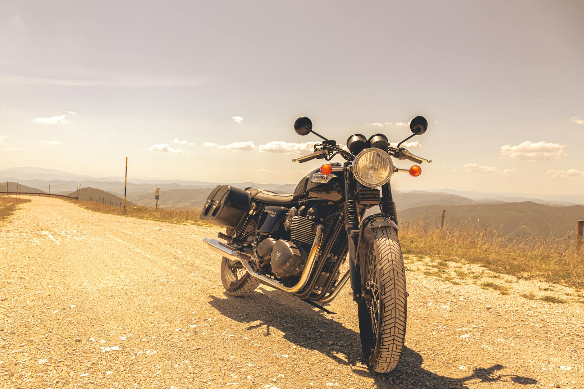 Zabytkowy motocykl na szutrowej drodze z widokiem na górskie szczyty