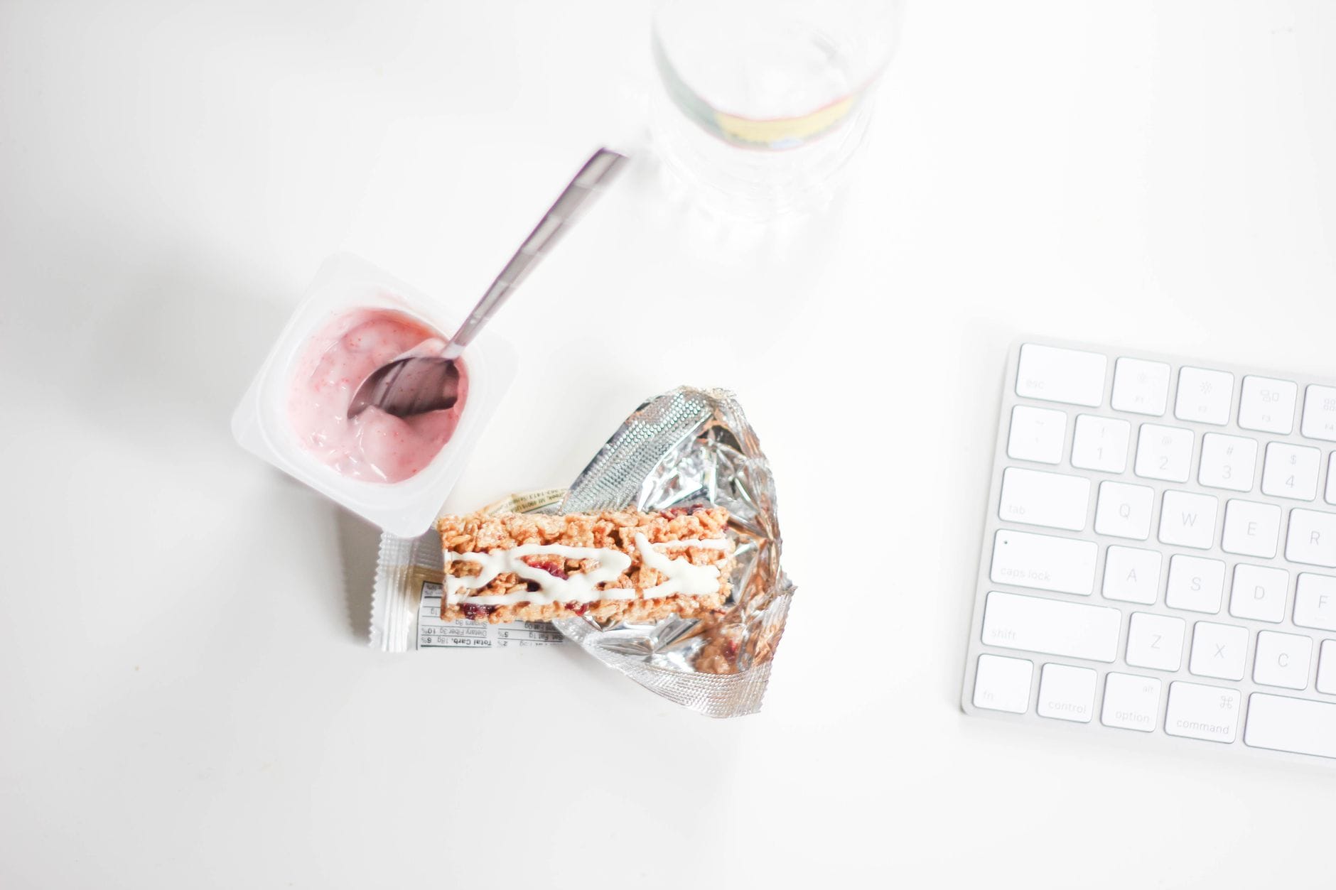 Jogurt i baton granola na biurku jako zdrowa przekąska przy pracy zdalnej