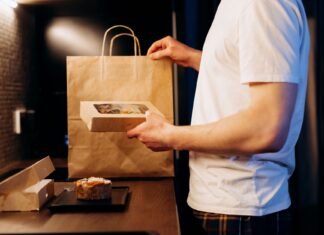 Mężczyzna rozpakowujący torbę z cateringiem dietetycznym w kuchni